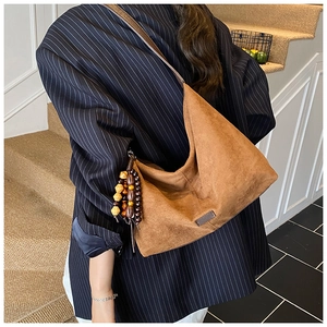 Detail of a brown suede tote bag with decorative vintage wooden beads and shoulder strap