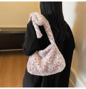 Detail of soft leopard print plush tote bag in pink and brown on a black blazer
