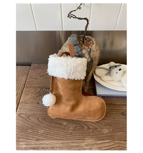 Close-up of suede boot-shaped handbag with plush trim and soft faux fur pom-pom detail