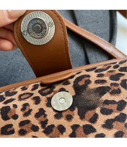 Detail of metal magnetic clasp with leopard print fabric and brown leather strap