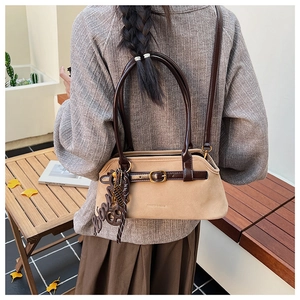 Detail of khaki suede shoulder bag with brown leather handles and autumn styling