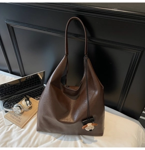 Detail of dark brown vintage faux leather tote bag with cute lamb plush charm