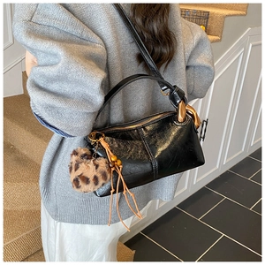 Detail of vintage black leather bag with chunky gold chain and leopard heart charm