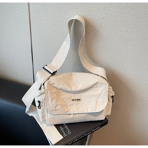 Detail of off-white casual crossbody bag showing fabric texture and adjustable strap