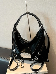 Glossy black high-capacity tote bag with silver hardware on a neutral background