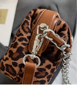 Detail of silver metal hook and brown leather trim on a leopard print handbag