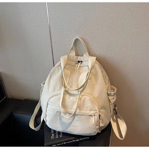 Detail of a cream-colored large capacity tote backpack with side drawstring pockets