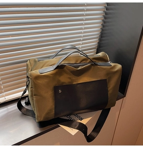 Detail of olive green canvas travel bag showing black leather straps and zip pocket