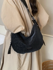 Classic black vintage leather hobo bag with silver hardware on model in beige trench coat