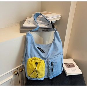 Dettaglio della borsa tote in nylon celeste con tasche gialle a coulisse e ampia tracolla