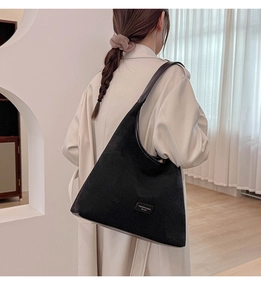 Detail of black suede hobo shoulder bag with fashion logo on minimal interior background