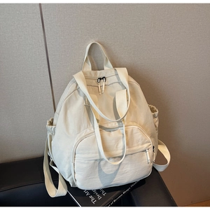 Detail of cream multi-functional nylon tote backpack showing straps and side pockets