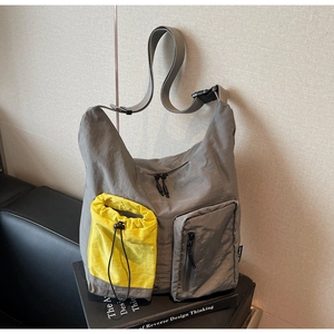 Dettaglio della borsa a tracolla in nylon con tasca gialla a coulisse e zip