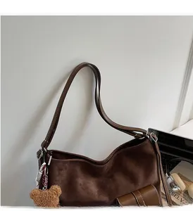Close-up of brown suede tote bag featuring a comfortable handle and cute bear charm