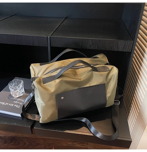 Detail of olive green travel bag with black leather handle and metal fastener
