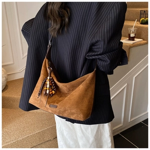 Detailed view of brown suede hobo bag with vintage wooden bead tassels and smooth matte finish