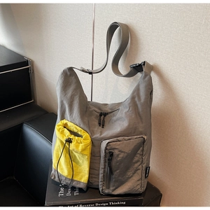 Dettaglio borsa a tracolla grigia con tasche utility e custodia gialla con coulisse