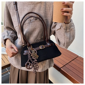Detail of vintage matte handbag with leather accents and unique decorative pendants