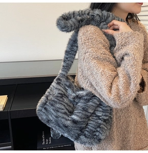 Detail of grey plush faux fur tote bag with wide strap on a model wearing brown knitwear