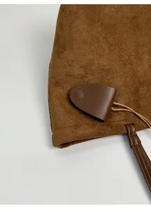 Dettaglio macro della borsa tote marrone opaca con ciondolo in pelle e cuciture precise