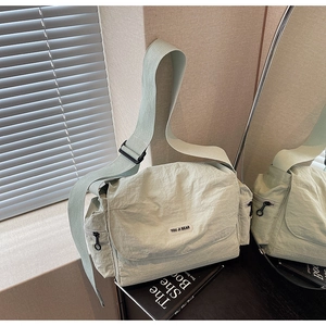 Detailed macro view of mint green nylon tote with pleated texture and side zipper