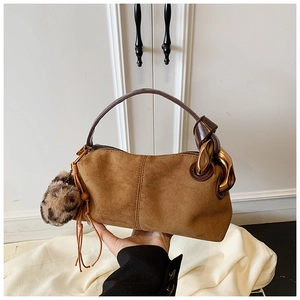 Detailed close-up of brown suede pillow bag with gold chain and leopard print charm