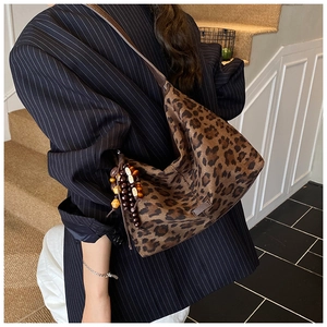 Detail of leopard print hobo bag with ethnic beaded tassel charm on a model