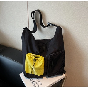 Dettaglio della borsa tote in nylon con tasca gialla a coulisse su un libro