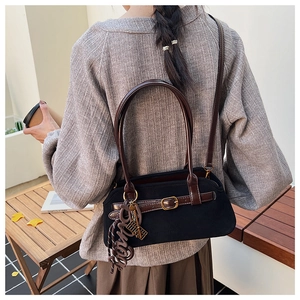 Detail of vintage black suede tote with brown leather strap and woven pendant accessory