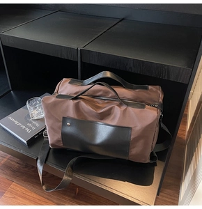 Close-up of brown canvas travel bag with leather trim and wide nylon strap in studio