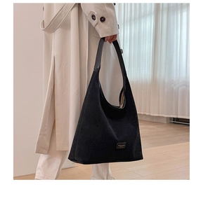 Detail of black hobo tote bag with metal logo plate showing fashion and bags est 1985 text