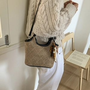 Détail du sac seau en suédine avec motifs matelassés et perles en bois décoratives