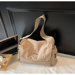Detail of light brown nylon messenger bag with brand logo and wide canvas shoulder strap