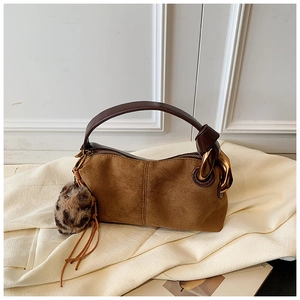 Detail of brown suede handbag with large gold metal ring and leopard print pompom
