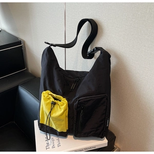 Dettaglio della borsa a tracolla in nylon nero con tasca gialla a coulisse e cerniere