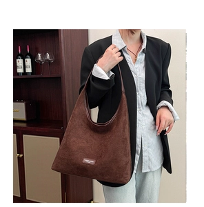 Macro detail of dark brown faux suede tote bag with rectangle fashion brand label