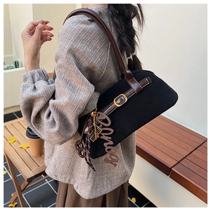 Detail of vintage matte black shoulder bag with brown leather strap and gold buckle