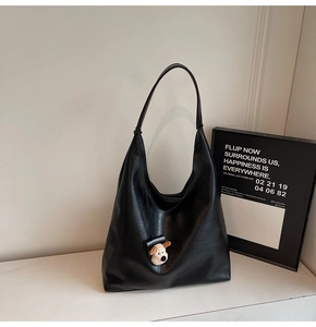 Detail of black faux leather tote bag with pebble texture and cute puppy charm