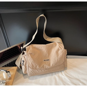 Detail view of khaki nylon messenger bag showing durable texture and brand logo patch