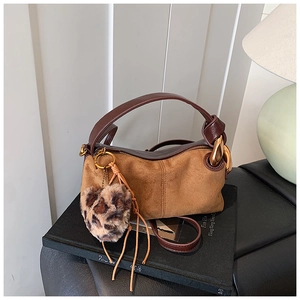 Detail of brown suede tote bag with leopard fur pompom and large golden ring hardware