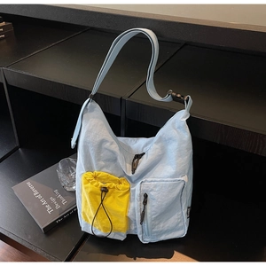Dettaglio della borsa a tracolla azzurra con tasca gialla a coulisse e tracolla regolabile