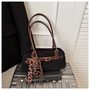 Detail of vintage matte black suede shoulder bag with brown leather handles and gold buckles
