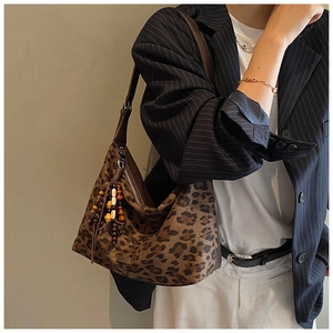 Detail of leopard print shoulder bag featuring textured fabric and decorative wooden beads