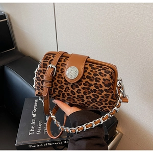 Close-up of leopard print pillow bag with brown leather trim and silver metal chain strap