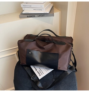 Detail view of durable brown travel bag with leather accents on a modern black stool
