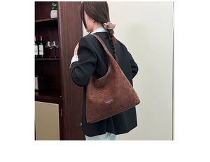 Close-up of deep brown corduroy hobo bag with a minimalist fashion logo detail