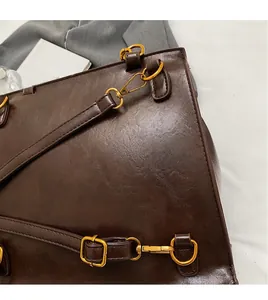 Close-up of durable golden metal hooks and premium brown leather texture on handbag