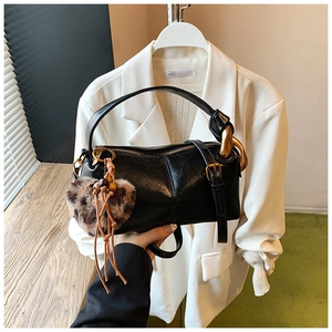 Detail of black matte leather pillow bag featuring gold hardware and leopard heart charm