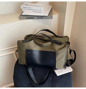 Detail of army green travel bag with black leather pockets and metal snaps on base