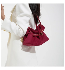 Dettaglio della borsa tote in pelle scamosciata bordeaux con anello dorato su modella